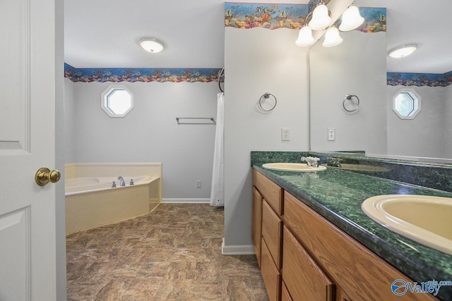 full bath with a sink, double vanity, a garden tub, and a healthy amount of sunlight