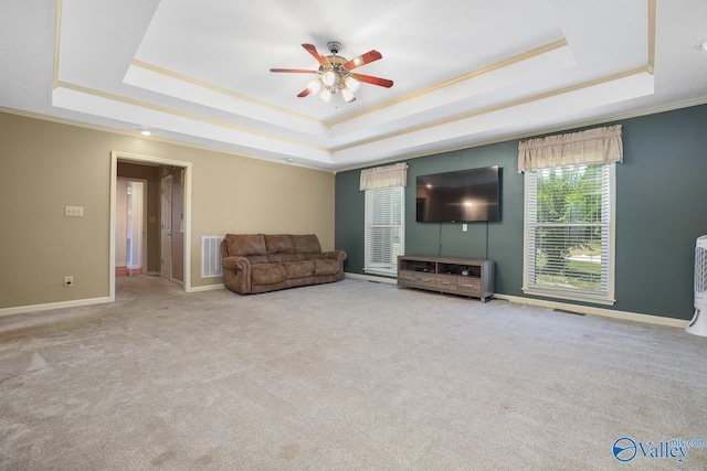 carpeted living room featuring visible vents, crown molding, a ceiling fan, a raised ceiling, and baseboards