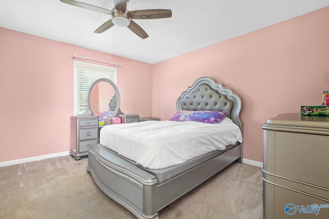 bedroom with light colored carpet, a textured ceiling, baseboards, and a ceiling fan
