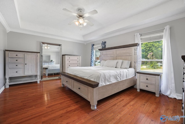 bedroom with hardwood / wood-style flooring, a raised ceiling, ornamental molding, and ceiling fan