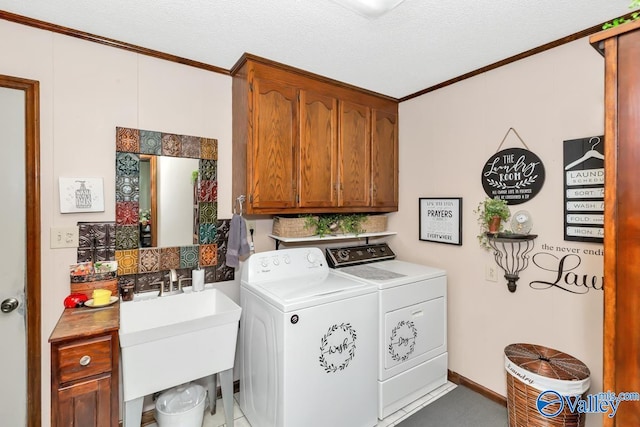 laundry area featuring cabinets, ornamental molding, a textured ceiling, and washer and dryer