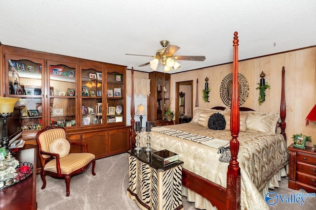 bedroom featuring ceiling fan, light colored carpet, a textured ceiling, and wood walls