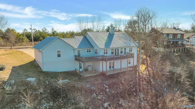 back of property featuring a lawn, a wooden deck, and a patio