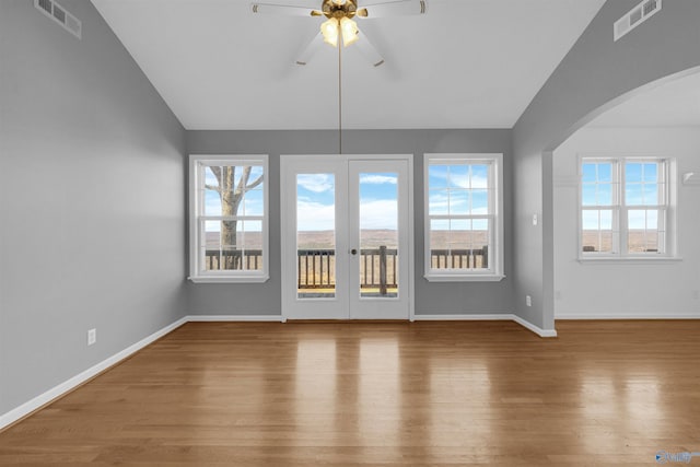 unfurnished living room featuring hardwood / wood-style flooring, vaulted ceiling, ceiling fan, and french doors