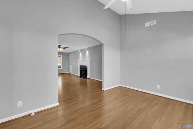 unfurnished living room with lofted ceiling, hardwood / wood-style flooring, and ceiling fan