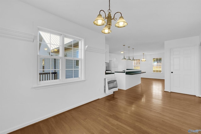 unfurnished living room with heating unit, a chandelier, and hardwood / wood-style floors