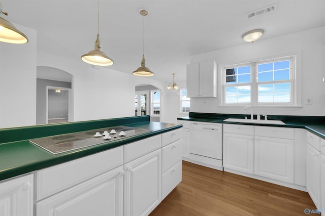 kitchen featuring white cabinets, stovetop, sink, hanging light fixtures, and white dishwasher