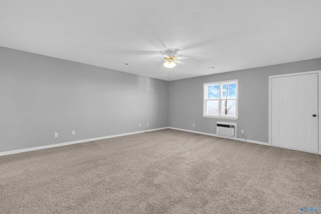 carpeted spare room featuring a wall unit AC and ceiling fan