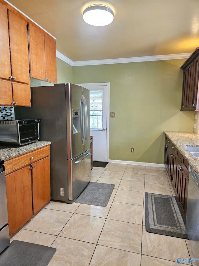 kitchen with backsplash, appliances with stainless steel finishes, light tile patterned floors, and crown molding