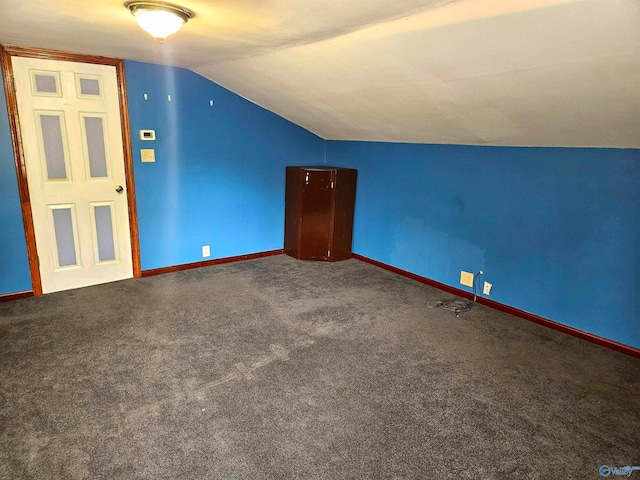 additional living space featuring dark colored carpet and lofted ceiling