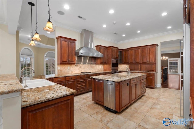 kitchen with a center island with sink, wall chimney range hood, hanging light fixtures, light stone countertops, and sink