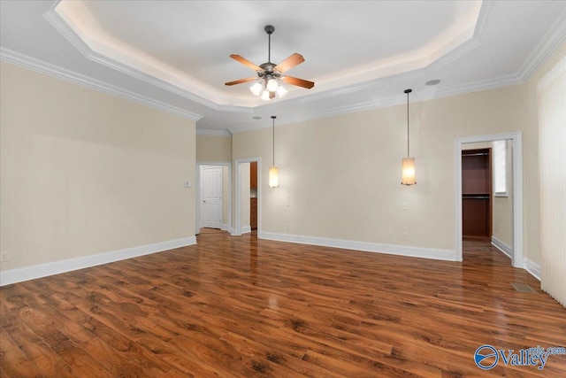 unfurnished room with a raised ceiling, dark hardwood / wood-style floors, and ornamental molding