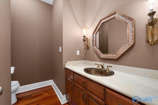 bathroom with toilet, vanity, and hardwood / wood-style floors