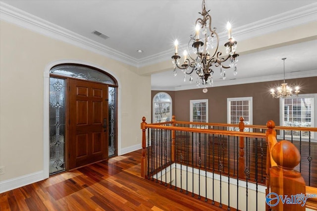 foyer with a healthy amount of sunlight, crown molding, a chandelier, and hardwood / wood-style floors