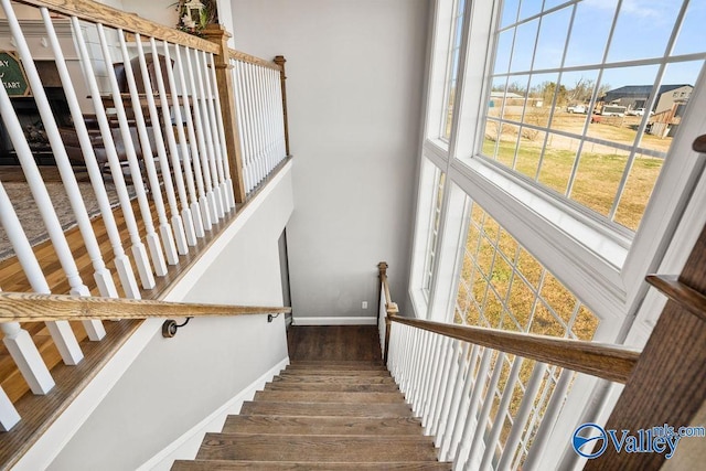 stairs with a towering ceiling, baseboards, and wood finished floors