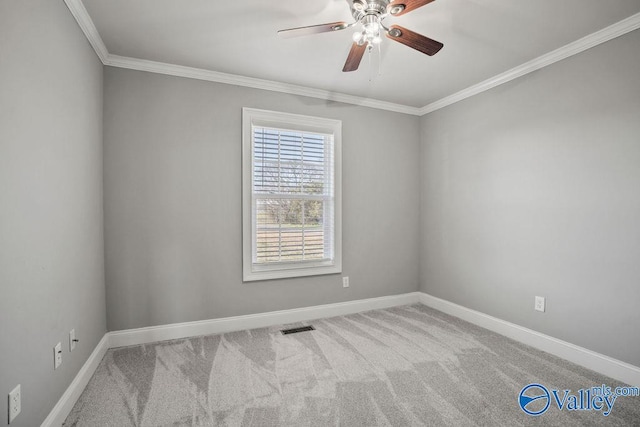 carpeted spare room featuring baseboards, ceiling fan, visible vents, and crown molding