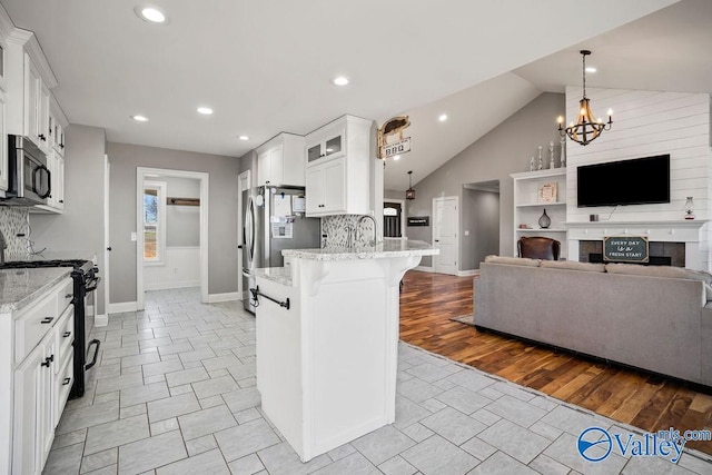 kitchen featuring stainless steel appliances, a breakfast bar, white cabinetry, open floor plan, and glass insert cabinets