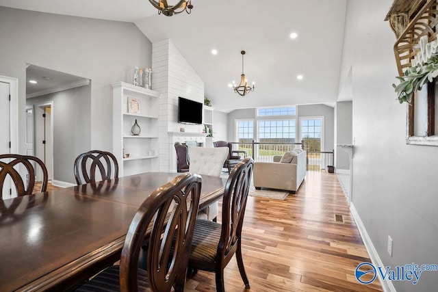 dining room with an inviting chandelier, light wood-style flooring, baseboards, and high vaulted ceiling