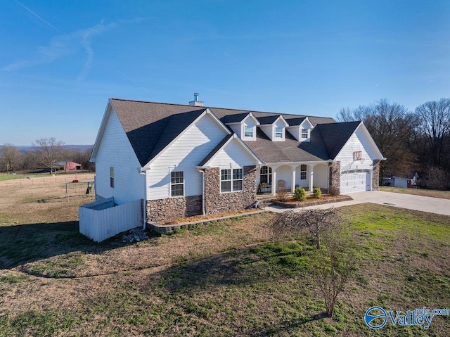 view of front of house with an attached garage, a front yard, fence, stone siding, and driveway