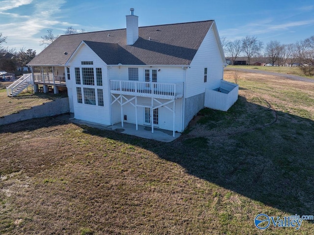 back of house with a shingled roof, a lawn, a chimney, stairs, and a patio area