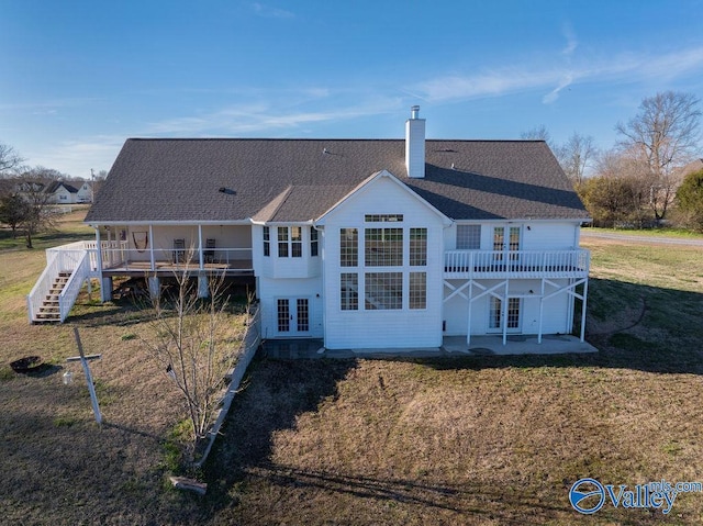 rear view of property featuring a lawn, a chimney, roof with shingles, french doors, and a patio area