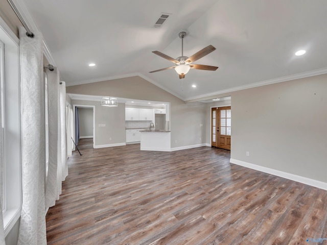unfurnished living room featuring visible vents, wood finished floors, baseboards, a sink, and vaulted ceiling