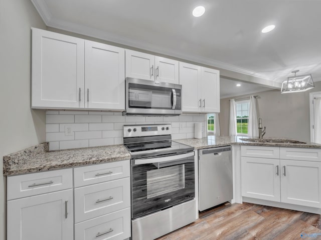 kitchen featuring appliances with stainless steel finishes, a sink, light wood-style floors, ornamental molding, and white cabinetry
