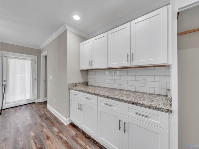 kitchen with decorative backsplash, light stone countertops, baseboards, ornamental molding, and white cabinetry