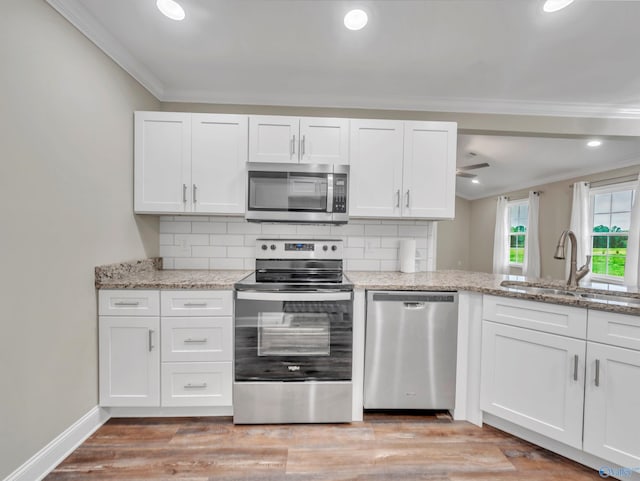 kitchen featuring a sink, white cabinets, ornamental molding, and stainless steel appliances