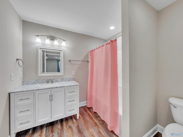 bathroom featuring toilet, baseboards, wood finished floors, and vanity