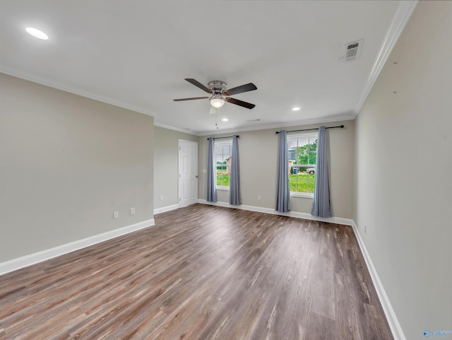 empty room with ceiling fan, visible vents, wood finished floors, baseboards, and ornamental molding