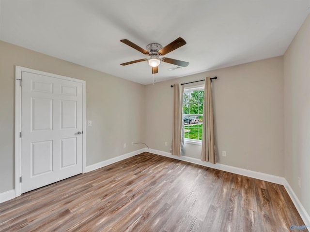 unfurnished room with baseboards, ceiling fan, wood finished floors, and visible vents