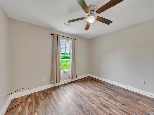 spare room featuring baseboards, ceiling fan, wood finished floors, and visible vents