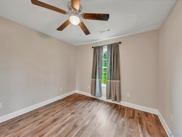empty room featuring baseboards, a ceiling fan, wood finished floors, and visible vents