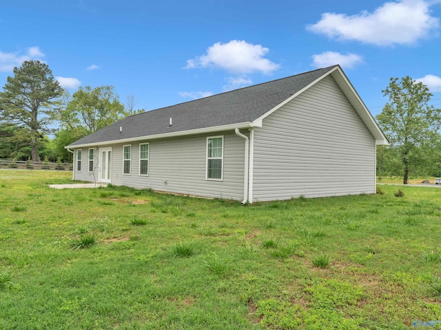 back of property with roof with shingles and a yard
