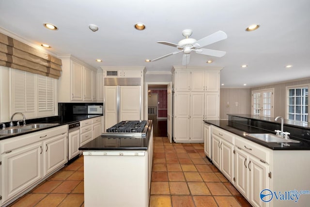 kitchen featuring a center island with sink, paneled built in fridge, and a sink