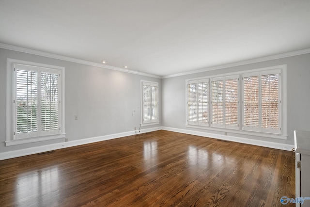 unfurnished room featuring baseboards, wood finished floors, visible vents, and crown molding