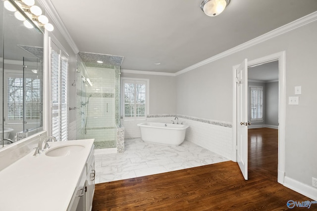 bathroom with a freestanding tub, wood finished floors, vanity, ornamental molding, and a stall shower