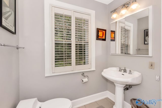 bathroom with baseboards, a sink, toilet, and tile patterned floors