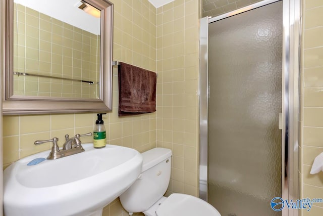 bathroom featuring a stall shower, decorative backsplash, toilet, a sink, and tile walls