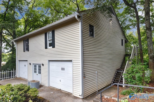 view of side of property with an attached garage and stairs