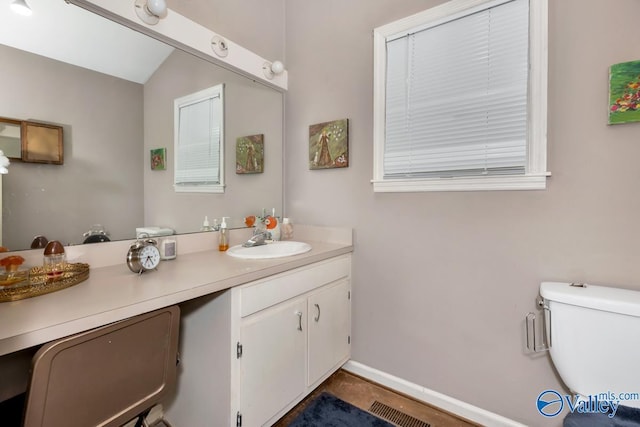 bathroom with toilet, vanity, visible vents, and baseboards