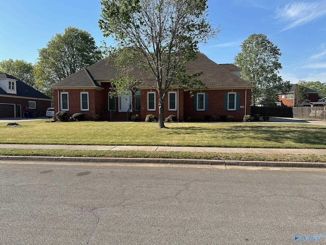 view of front facade with brick siding, a front lawn, and fence
