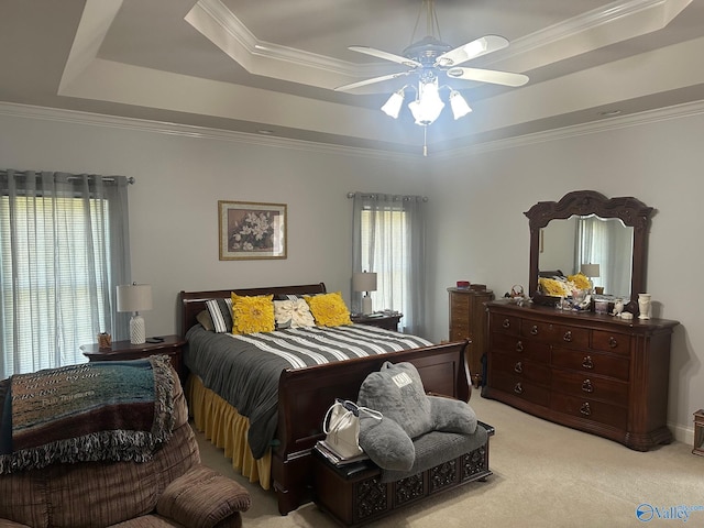 bedroom featuring light colored carpet, ornamental molding, a ceiling fan, and a tray ceiling