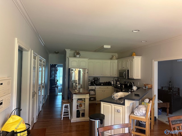 kitchen with dark countertops, appliances with stainless steel finishes, a peninsula, dark wood-type flooring, and ornamental molding