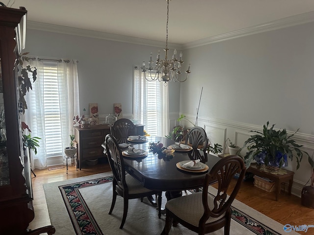 dining space with crown molding, an inviting chandelier, and wood finished floors