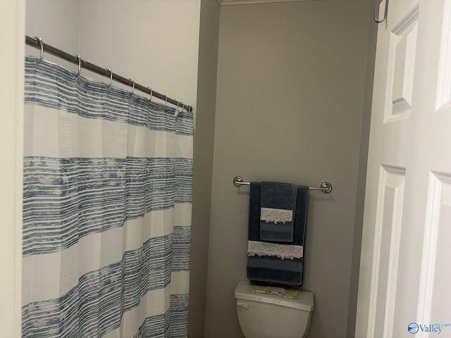 bathroom featuring toilet and curtained shower