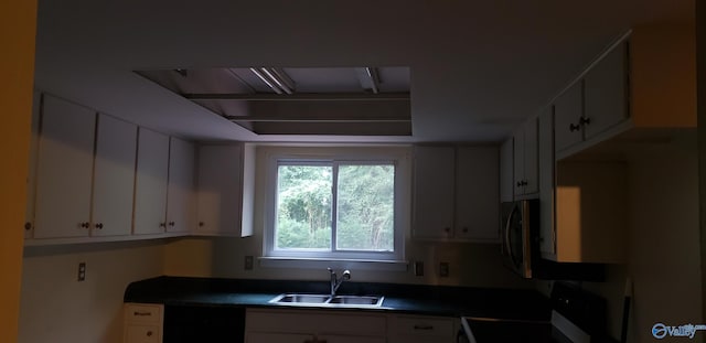 kitchen featuring sink, white cabinets, and range