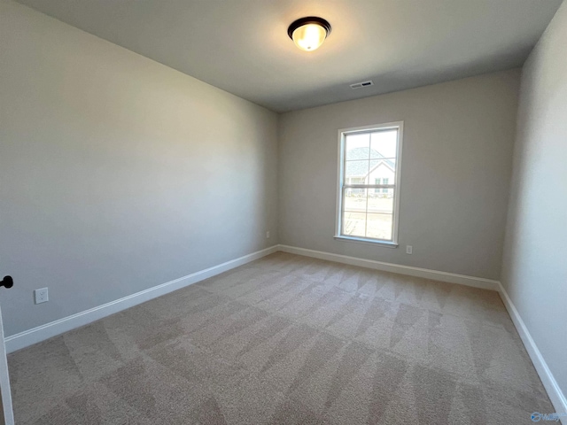 spare room featuring light colored carpet, visible vents, and baseboards