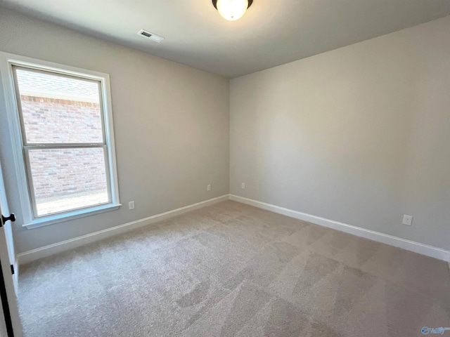 empty room featuring light colored carpet, visible vents, and baseboards